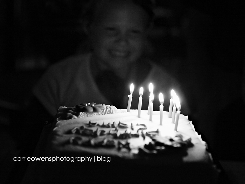 black and white image of girl blowing out candles