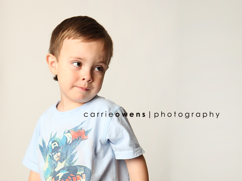 salt lake city utah child photographer Carrie Owens captures coy young boy as he warms up to the camera in the studio