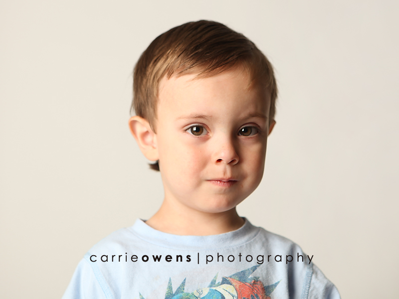 salt lake city utah child photographer Carrie Owens captures serious and silly young boy as he warms up to the camera in the studio